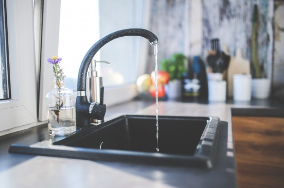 black kitchen sink with water flowing from black mixer tap
