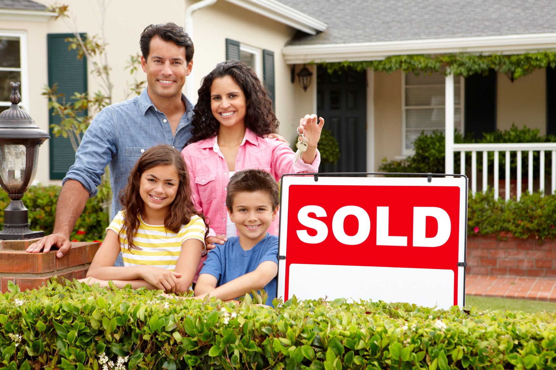 family in front of a house with sold sign