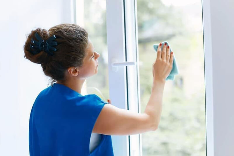 woman in blue cleaning window treatment